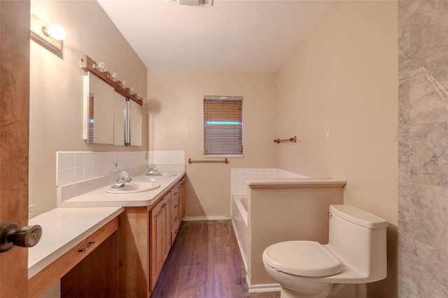 bathroom featuring a garden tub, toilet, backsplash, wood finished floors, and vanity