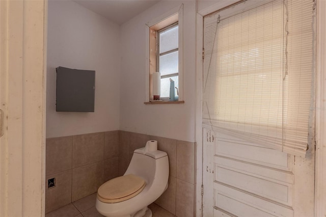 bathroom featuring a wainscoted wall, toilet, tile walls, and tile patterned flooring