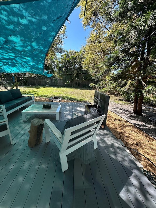 wooden terrace featuring a yard, a fenced backyard, and an outdoor living space with a fire pit