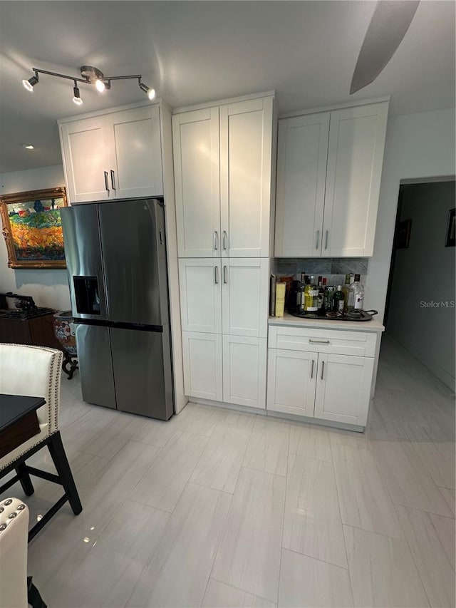 kitchen featuring decorative backsplash, stainless steel fridge with ice dispenser, and white cabinetry