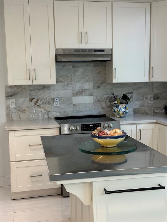 kitchen with white cabinetry, a kitchen island, under cabinet range hood, stainless steel electric range, and decorative backsplash