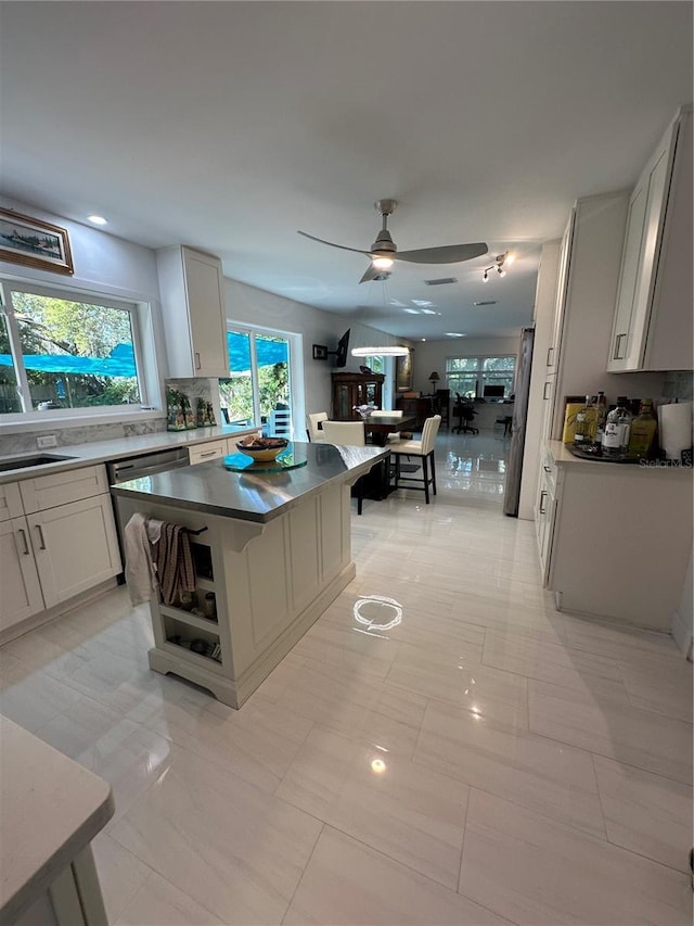 kitchen with white cabinets, dishwasher, freestanding refrigerator, a ceiling fan, and backsplash