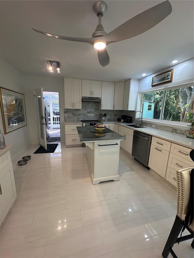 kitchen with a sink, under cabinet range hood, stainless steel appliances, backsplash, and a kitchen island