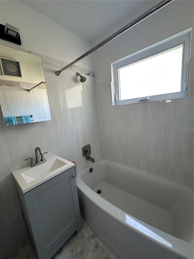 full bath with bathing tub / shower combination, vanity, and tile walls