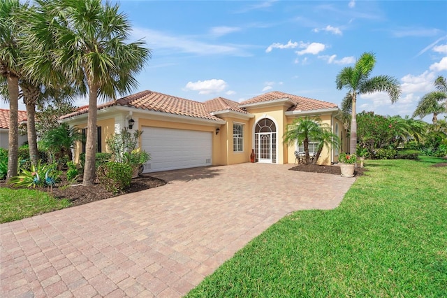 mediterranean / spanish-style house with stucco siding, a tiled roof, a front yard, and a garage