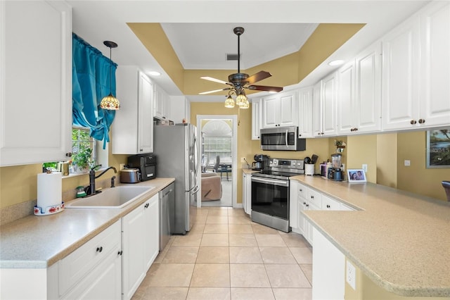 kitchen featuring light countertops, appliances with stainless steel finishes, a peninsula, white cabinetry, and a sink