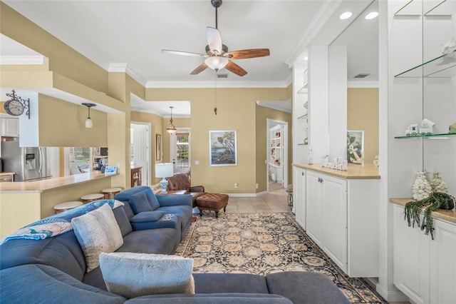 living area with a ceiling fan, baseboards, visible vents, light tile patterned flooring, and ornamental molding