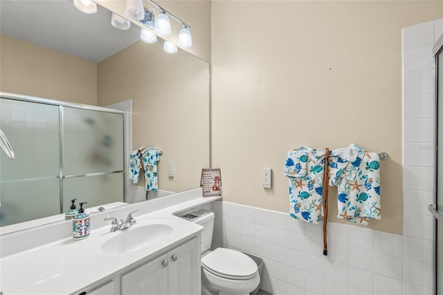 bathroom featuring tile walls, a shower stall, toilet, and vanity