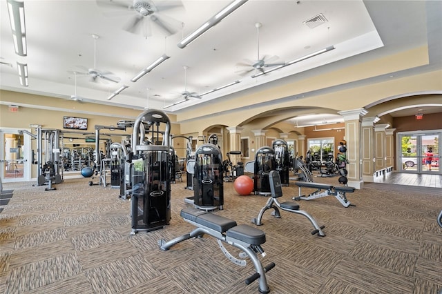 gym featuring carpet, visible vents, ornate columns, arched walkways, and ceiling fan