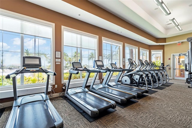 gym with baseboards, a tray ceiling, and carpet