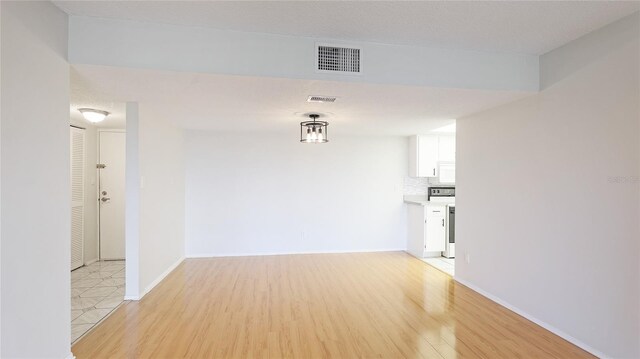 empty room featuring baseboards, visible vents, and light wood finished floors