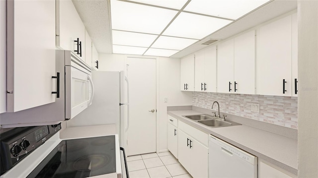 kitchen featuring a sink, backsplash, white appliances, light countertops, and light tile patterned floors