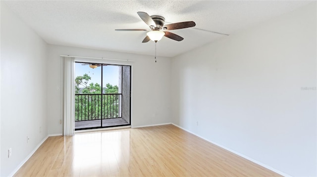 spare room featuring light wood finished floors, baseboards, a textured ceiling, and a ceiling fan