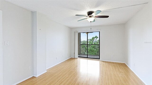 spare room featuring light wood finished floors, ceiling fan, a textured ceiling, and baseboards