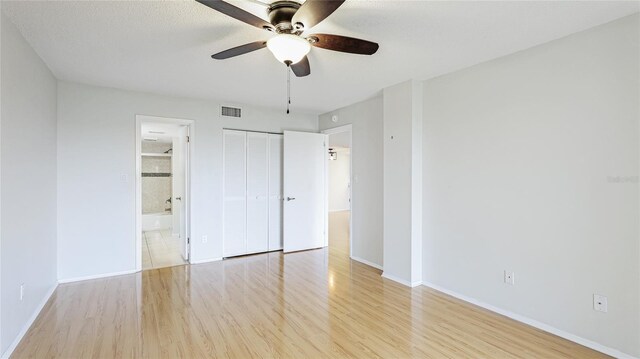 unfurnished bedroom featuring visible vents, a ceiling fan, wood finished floors, connected bathroom, and baseboards