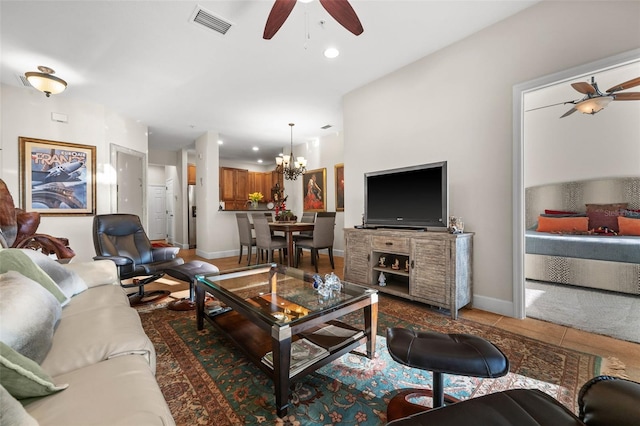 living room featuring recessed lighting, visible vents, baseboards, and ceiling fan with notable chandelier