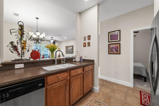 kitchen featuring visible vents, a sink, dark countertops, appliances with stainless steel finishes, and brown cabinetry