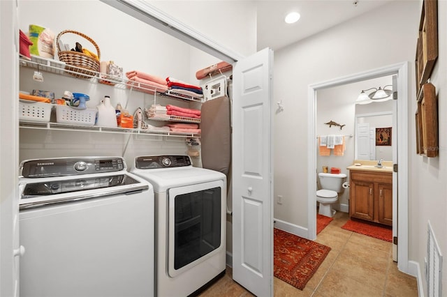 washroom featuring baseboards, visible vents, laundry area, light tile patterned flooring, and washer and clothes dryer