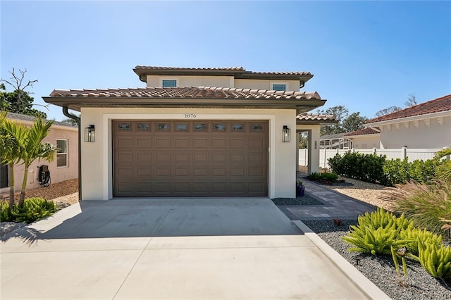 mediterranean / spanish home with stucco siding, concrete driveway, an attached garage, and fence