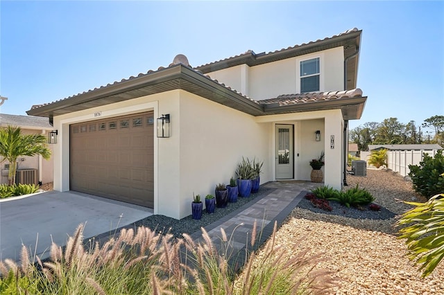 mediterranean / spanish home with concrete driveway, an attached garage, central AC unit, and stucco siding