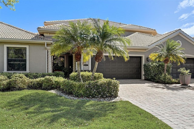 view of front facade with stucco siding, decorative driveway, an attached garage, and a tiled roof