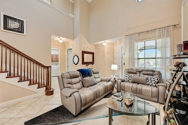 living area featuring stairway, baseboards, washer / clothes dryer, tile patterned flooring, and a towering ceiling