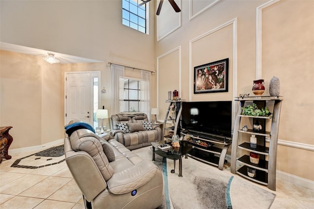 living area featuring tile patterned floors, baseboards, a towering ceiling, and ceiling fan