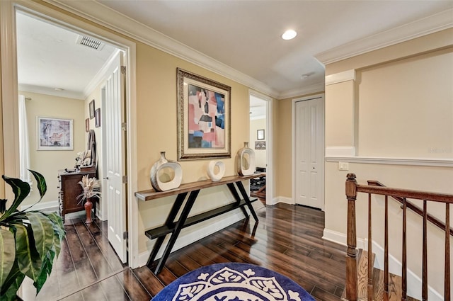 hallway featuring dark wood-style floors, visible vents, baseboards, crown molding, and an upstairs landing