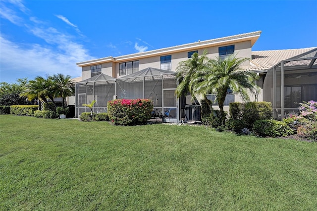 rear view of property featuring a lanai, stucco siding, and a yard