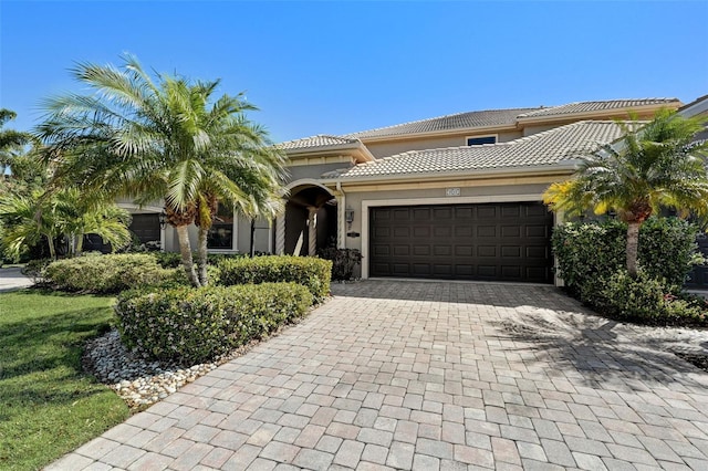 mediterranean / spanish-style home featuring stucco siding, decorative driveway, an attached garage, and a tile roof