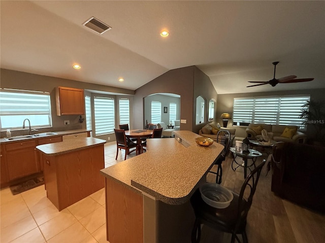 kitchen with visible vents, a center island, open floor plan, arched walkways, and a sink