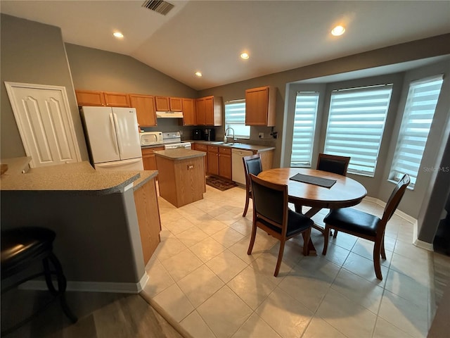 kitchen featuring visible vents, a kitchen island, under cabinet range hood, white appliances, and a sink