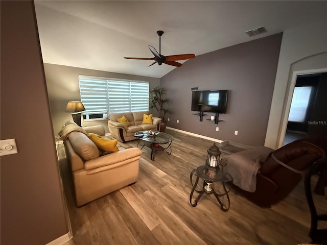 living area with visible vents, wood finished floors, baseboards, ceiling fan, and vaulted ceiling