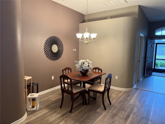 dining area featuring visible vents, wood finished floors, baseboards, and a chandelier