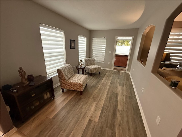 living area featuring baseboards, arched walkways, and wood finished floors