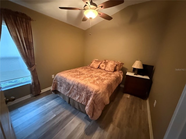 bedroom with a ceiling fan, lofted ceiling, wood finished floors, and baseboards