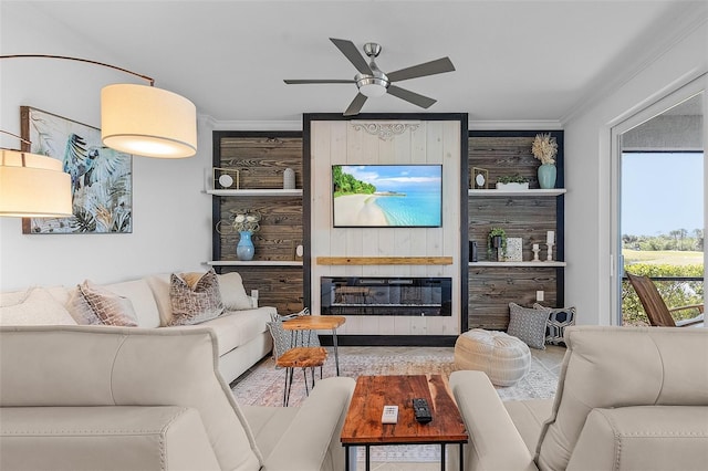 living area with a glass covered fireplace, ceiling fan, and ornamental molding