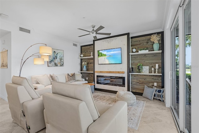 living room featuring a glass covered fireplace, a ceiling fan, visible vents, and ornamental molding