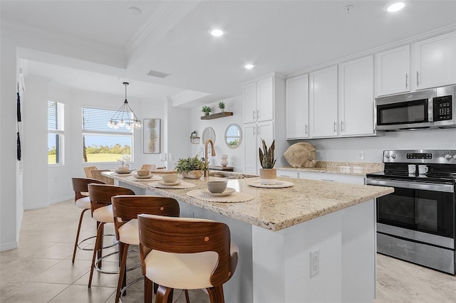 kitchen featuring visible vents, ornamental molding, white cabinetry, appliances with stainless steel finishes, and light stone countertops