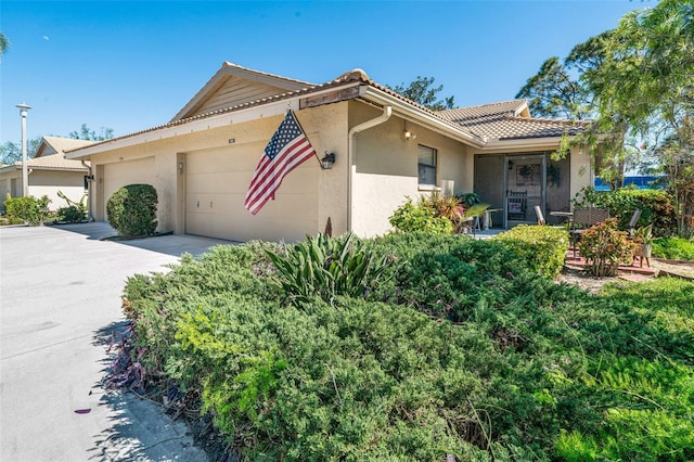 single story home with a tile roof, an attached garage, driveway, and stucco siding