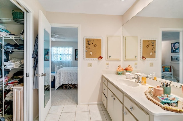 ensuite bathroom featuring vanity, ensuite bath, ceiling fan, a walk in closet, and tile patterned floors