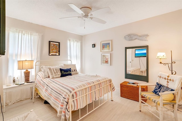 bedroom with a ceiling fan, light wood finished floors, and a textured ceiling