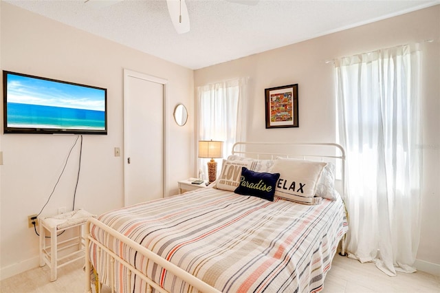 bedroom featuring baseboards, multiple windows, a textured ceiling, and a ceiling fan