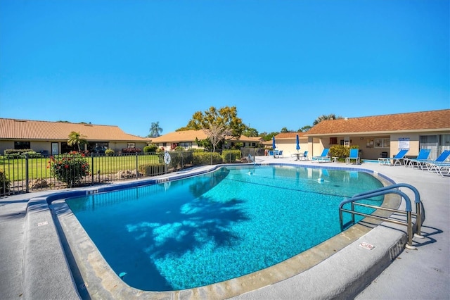 community pool with a patio and fence