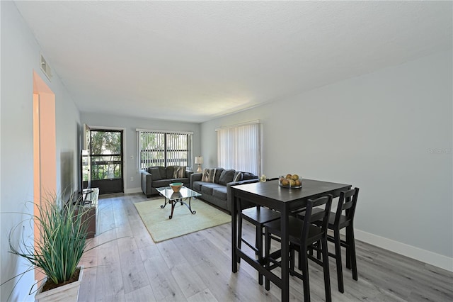 dining area featuring visible vents, baseboards, and light wood finished floors