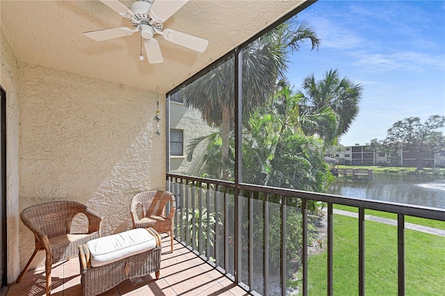 sunroom featuring plenty of natural light, a ceiling fan, and a water view