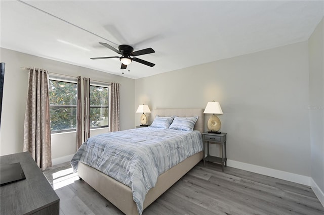 bedroom featuring ceiling fan, baseboards, and light wood-style flooring