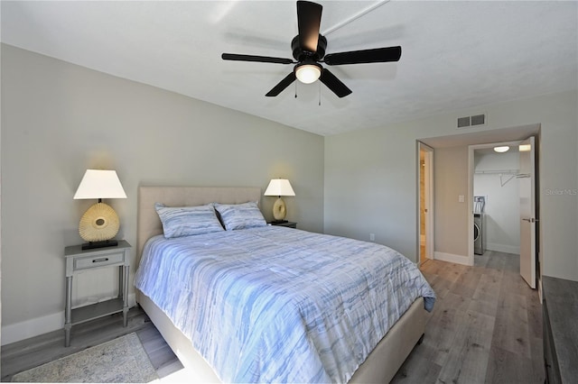 bedroom with a ceiling fan, wood finished floors, visible vents, and baseboards