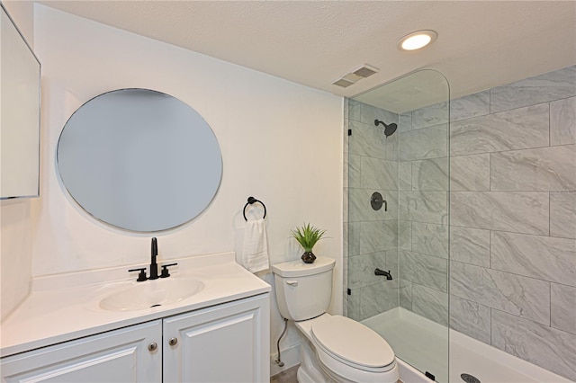 bathroom featuring visible vents, tiled shower, toilet, and vanity