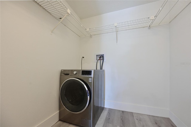 laundry area with washer / dryer, baseboards, light wood finished floors, and laundry area